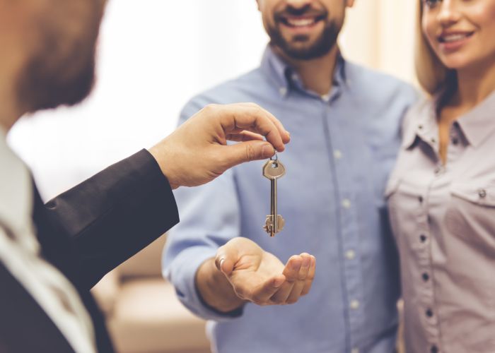 Landlord handing over keys to young couple